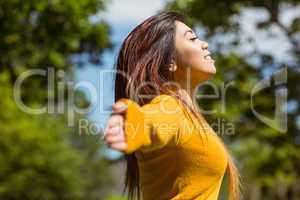 Beautiful woman with arms outstretched in park