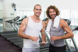 Smiling male trainer and fit man at gym