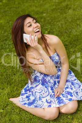 Cheerful woman using mobile phone in park