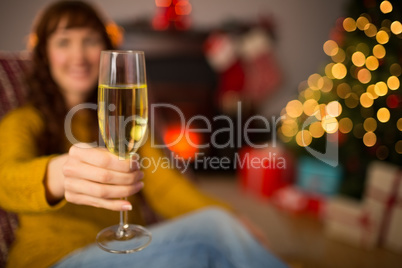 Redhead holding glass of champagne on couch at christmas