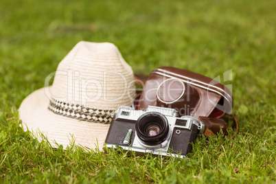 Vintage camera with his cover near a straw hat