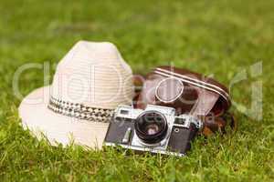 Vintage camera with his cover near a straw hat