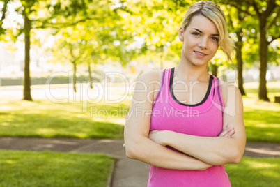 Fit blonde smiling at camera in the park