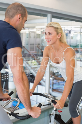 Smiling fit couple working on exercise bikes at gym