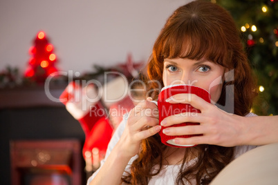 Pretty redhead sitting on couch drinking hot chocolate