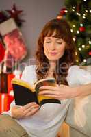 Cheerful redhead sitting on the floor reading