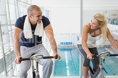 Fit couple working on exercise bikes at gym