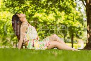 Relaxed young woman sitting on grass at park