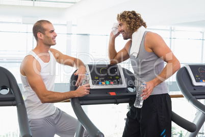 Smiling trainer talking to fit man at gym