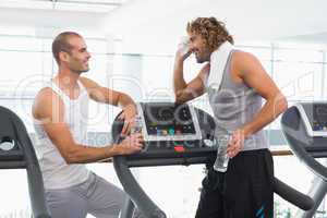 Smiling trainer talking to fit man at gym