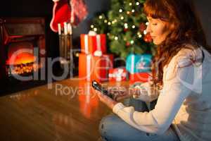 Smiling redhead using smartphone at christmas