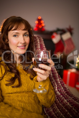 Woman sitting on a couch while holding a glass of red wine