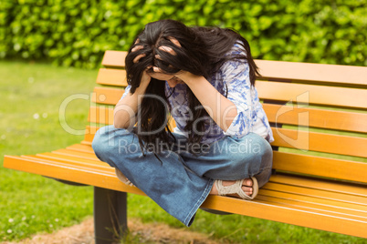 Brunette sitting on bench thinking