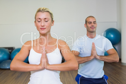 Couple with joined hands and eyes closed at fitness studio