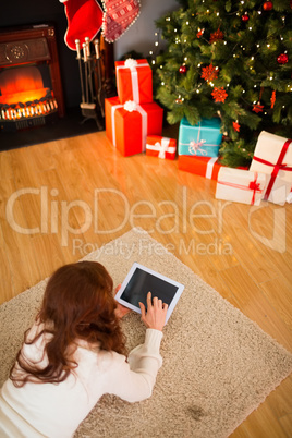 Redhead woman lying on floor using tablet at christmas