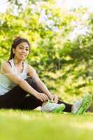 Healthy woman relaxing in park as she ties shoelace