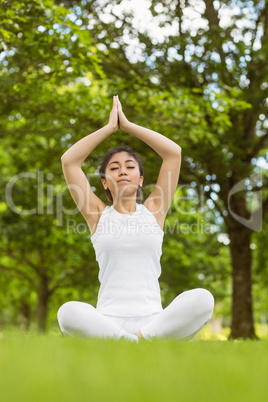 Healthy woman sitting with joined hands at park