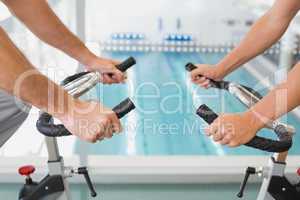 Mid section of couple working on exercise bikes at gym