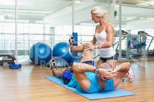 Trainer assisting man with exercises at fitness studio