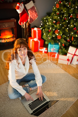 Redhead woman sitting on floor using laptop at christmas