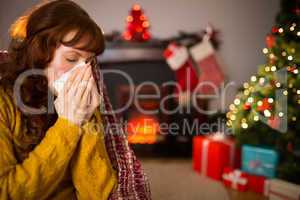 Woman sitting on sofa and blowing her nose at christmas
