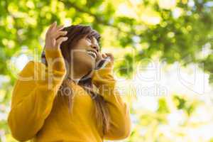 Cheerful woman using mobile phone in park