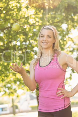 Fit blonde tossing green apple