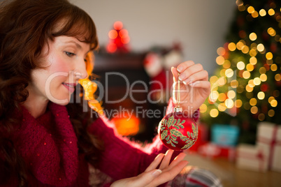 Cheerful redhead holding red bauble