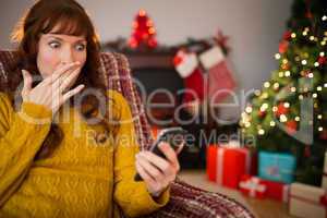 Surprised redhead looking her mobile at christmas