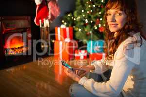 Smiling redhead using smartphone at christmas