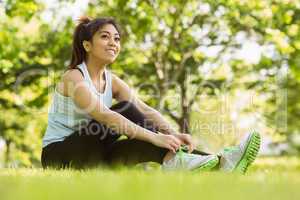 Healthy woman relaxing in park as she ties shoelace