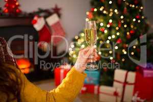Redhead holding glass of champagne on couch at christmas