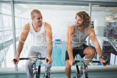 Fit men working on exercise bikes at gym