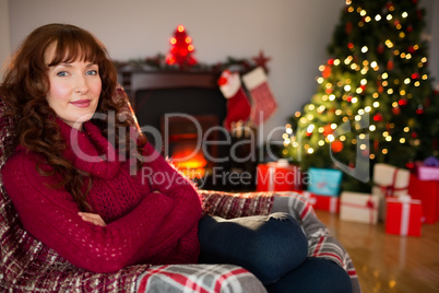 Pretty redhead in jumper sitting on the armchair at christmas