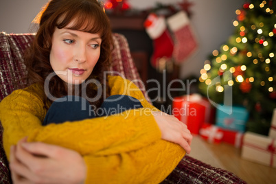 Thoughtful redhead sitting on the armchair at christmas