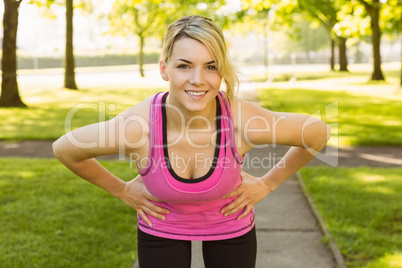 Fit blonde smiling at camera in the park