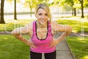 Fit blonde smiling at camera in the park