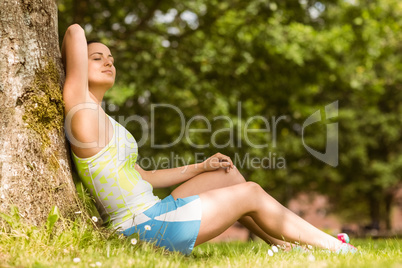 Relaxed fit brunette sitting against a tree