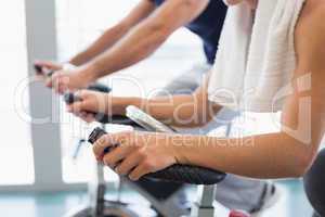 Mid section of fit couple working on exercise bikes at gym
