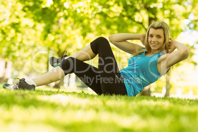 Fit blonde doing sit ups in the park