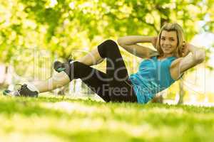 Fit blonde doing sit ups in the park