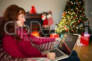 Content redhead using laptop at christmas