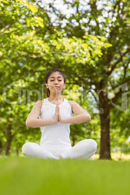 Healthy woman sitting with joined hands at park