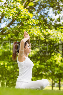 Healthy woman sitting with joined hands over head at park
