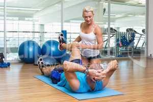 Trainer assisting man with exercises at fitness studio