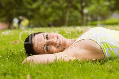 Smiling brunette lying on the grass