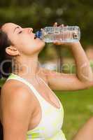 Fit brunette in sportswear drinking water