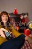 Woman changing channels with remote control at christmas