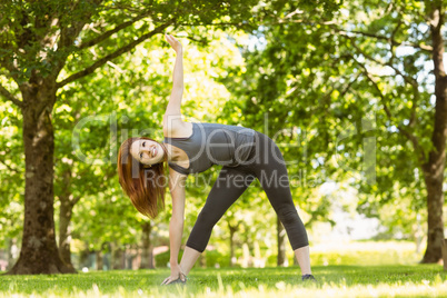 Pretty athletic redhead stretching in park