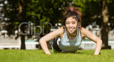 Healthy woman doing push ups in park